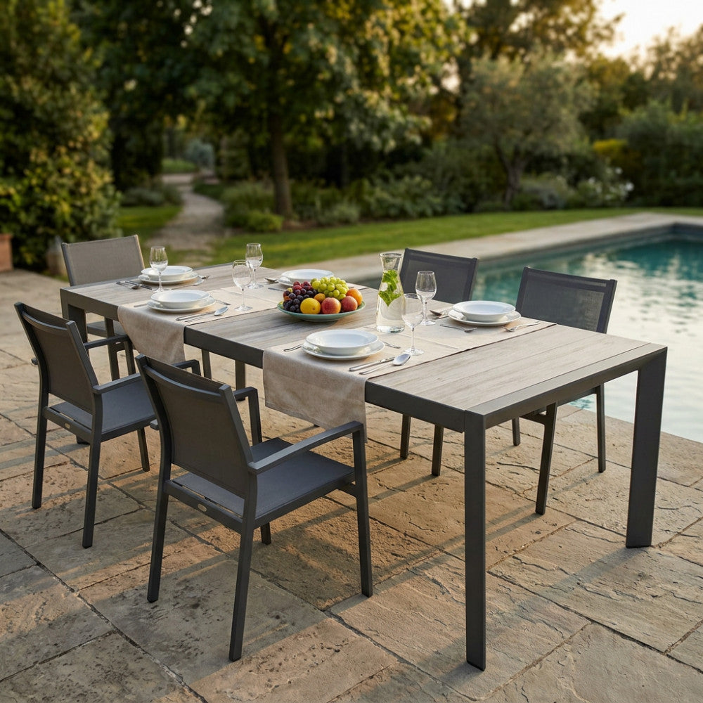 Tavolo da giardino Portland estensibile in alluminio antracite e gres, allestito per un pranzo all'aperto a bordo piscina.