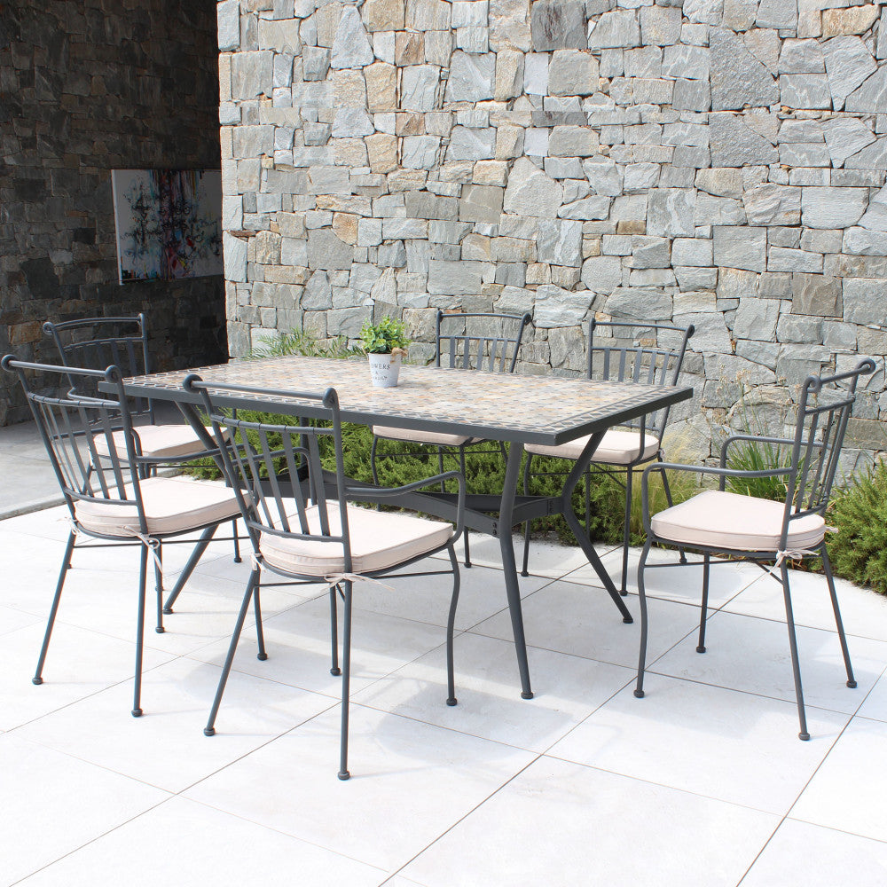 Set da pranzo completo con il tavolo in ceramica e sei sedie in metallo abbinate con cuscini su una terrazza chiara.
