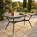 Tavolo da giardino Minosse in ceramica antracite allestito con brocca e frutta su un patio soleggiato.