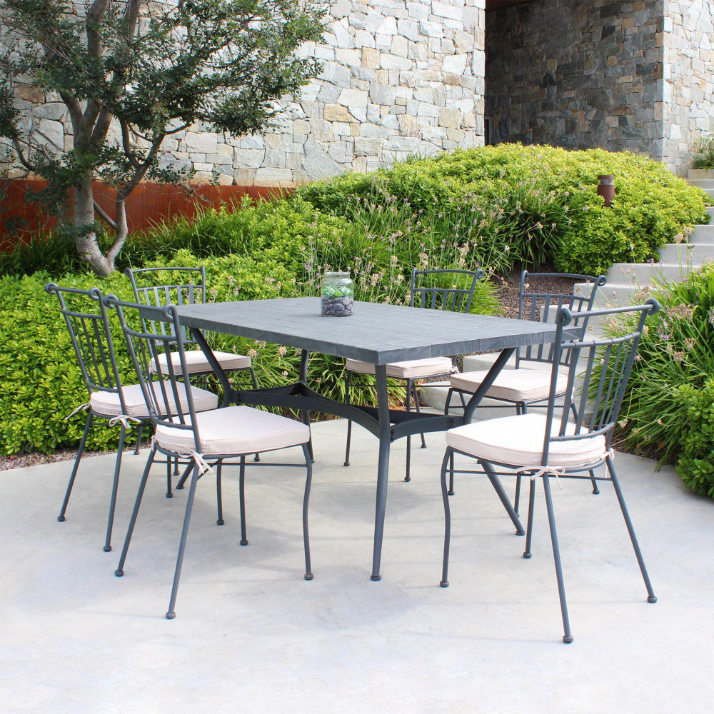 Set da pranzo outdoor con tavolo Minosse in ceramica e sei sedie in metallo con cuscini su una terrazza.