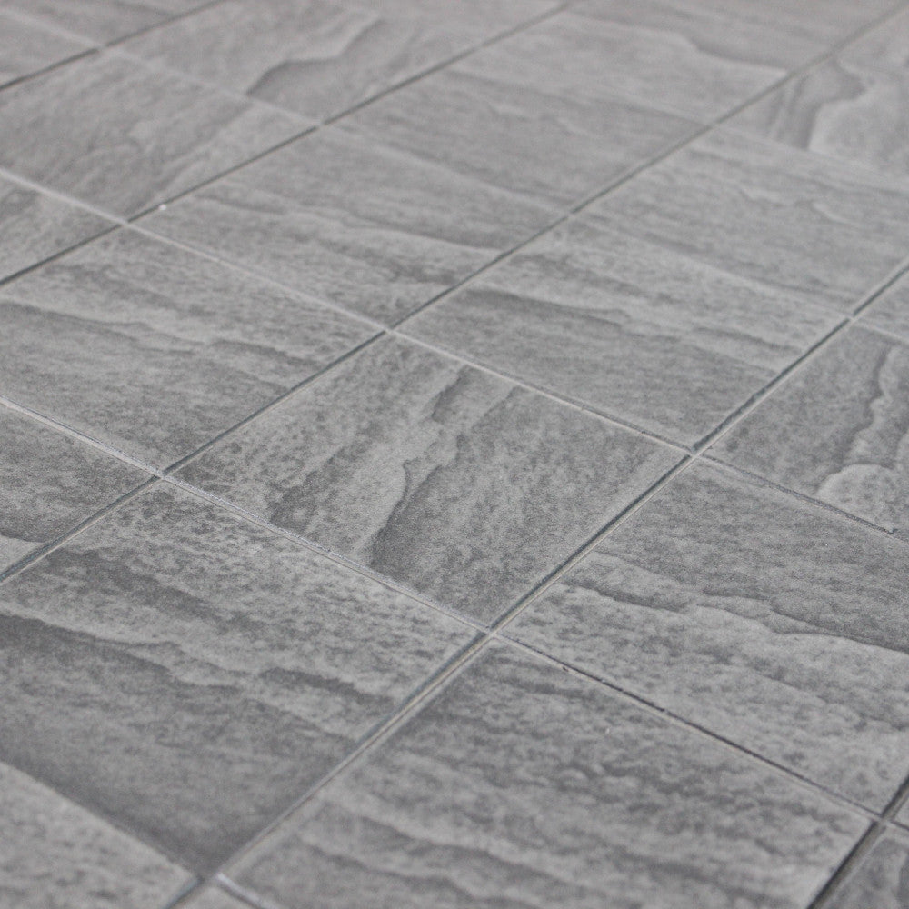 Primo piano della superficie in ceramica grigio scuro del tavolo Minosse, che evidenzia la texture materica.
