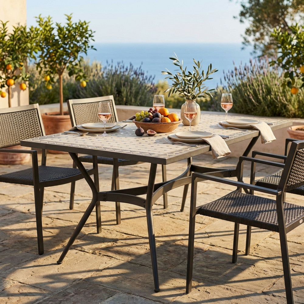 Tavolo da giardino Prometeo in ceramica antracite e beige, allestito per un pranzo all'aperto con vista mare.