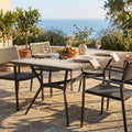 Tavolo da giardino Prometeo in ceramica antracite e beige, allestito per un pranzo all'aperto con vista mare.