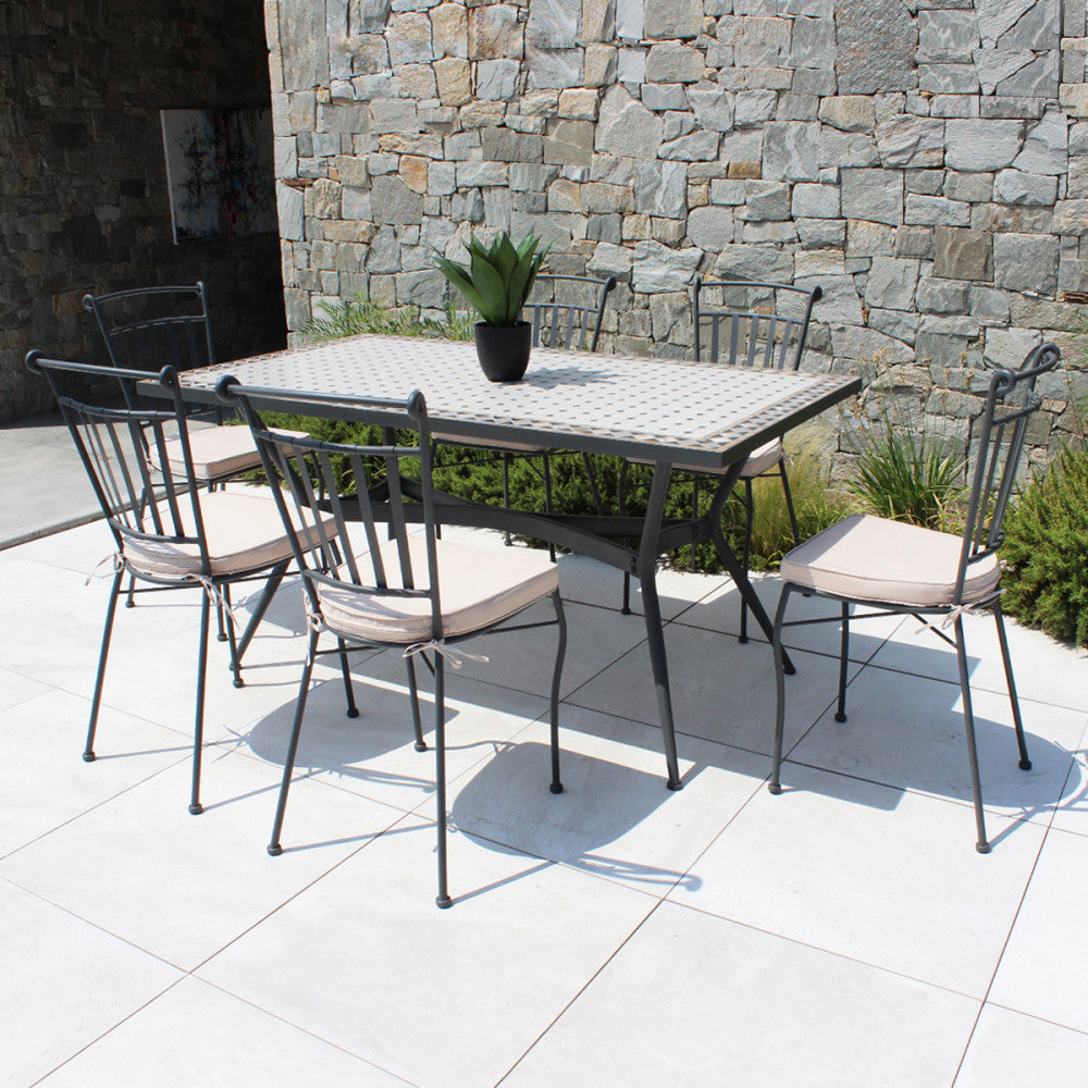 Set da pranzo esterno con il tavolo Prometeo e sei sedute, posizionato su un patio moderno in pietra.