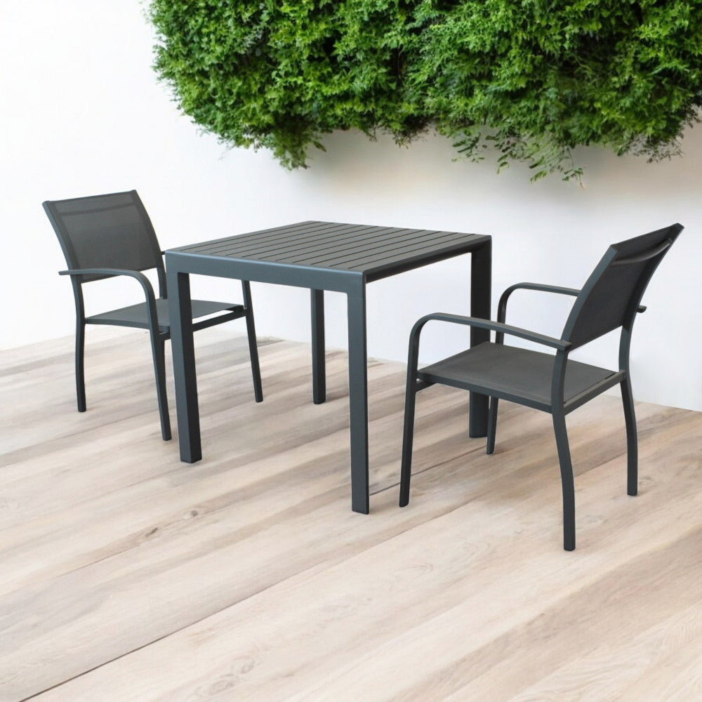 Tavolo moderno Rosario abbinato a due sedie in un patio minimalista con parete verde.