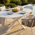 Tavolo da giardino Camelot in alluminio bianco allestito per un pranzo all'aperto a bordo piscina.