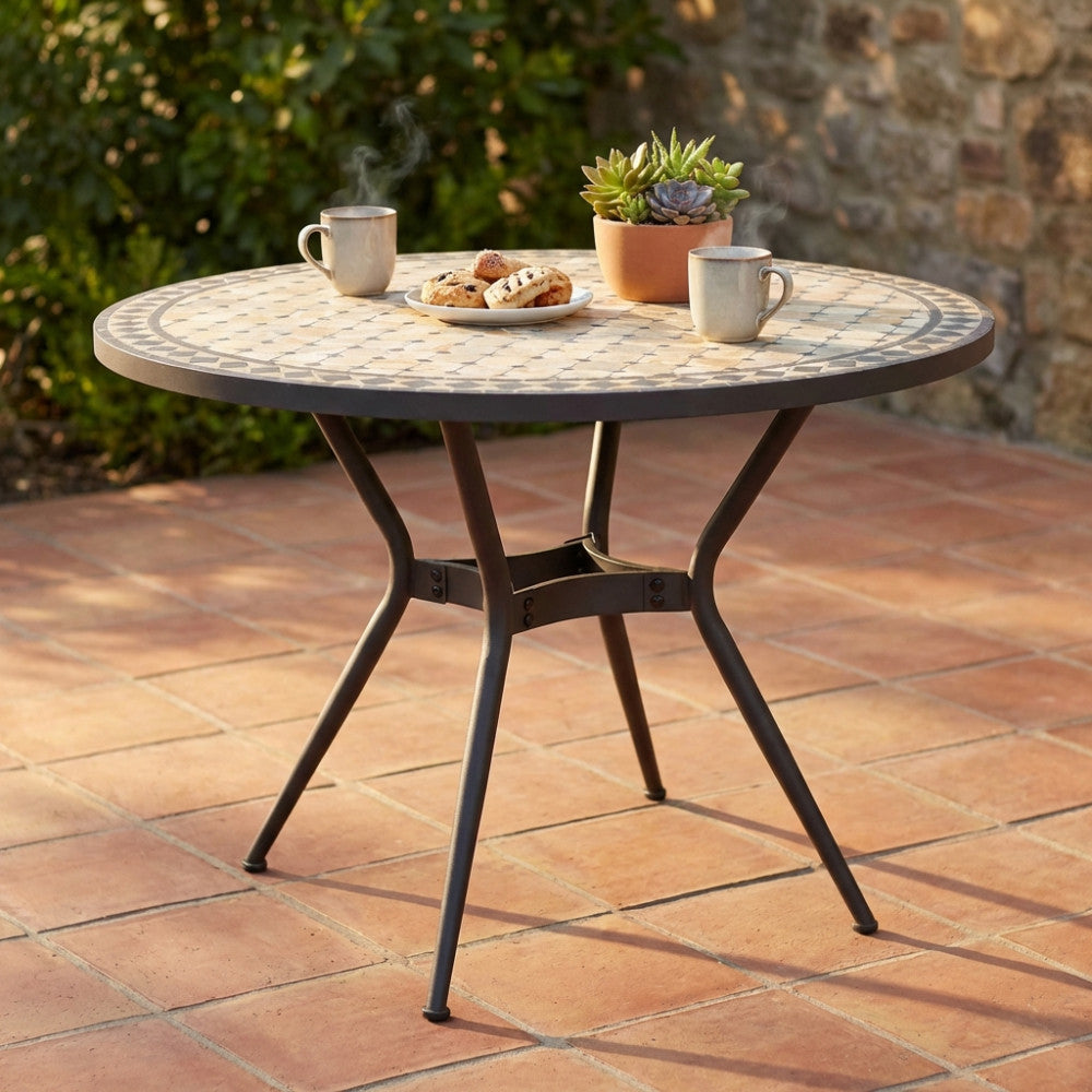 Tavolo da giardino rotondo in ceramica con motivo a mosaico antracite e beige, allestito con caffè su un patio in cotto.