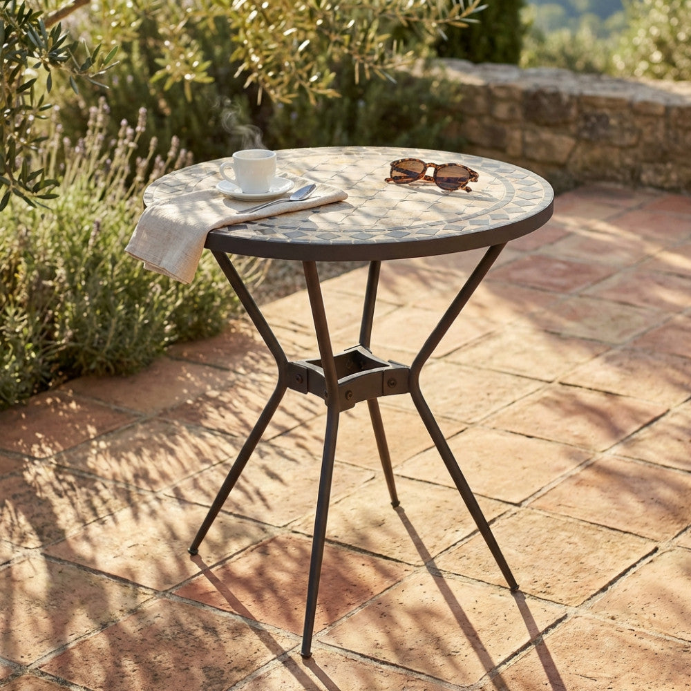 Tavolo da giardino rotondo in ceramica su pavimentazione in cotto con tazzina da caffè.