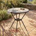 Tavolo da giardino rotondo in ceramica su pavimentazione in cotto con tazzina da caffè.