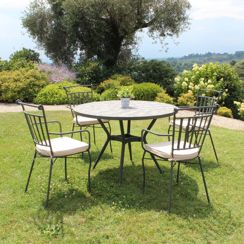 Set completo con il tavolo Zefiro e quattro sedie in ferro battuto su un prato verde.