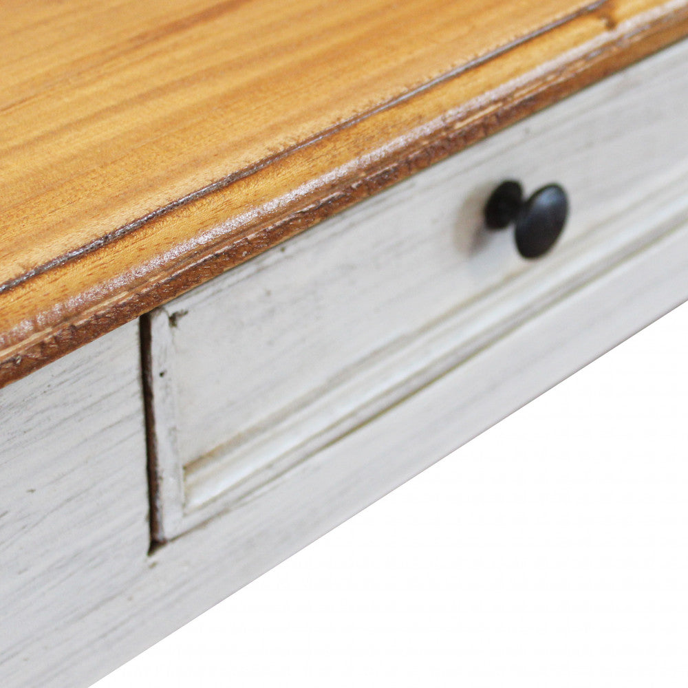 Dettaglio del profilo del tavolo Russell, con focus sul contrasto tra il top in legno naturale e il cassetto bianco anticato.