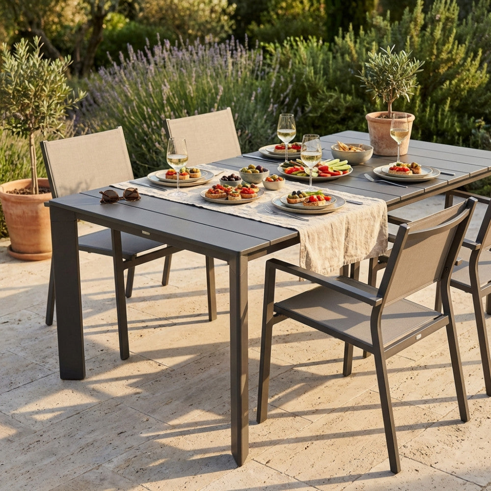 Dettaglio del tavolo Sacramento color taupe con sedute coordinate in un rigoglioso giardino.