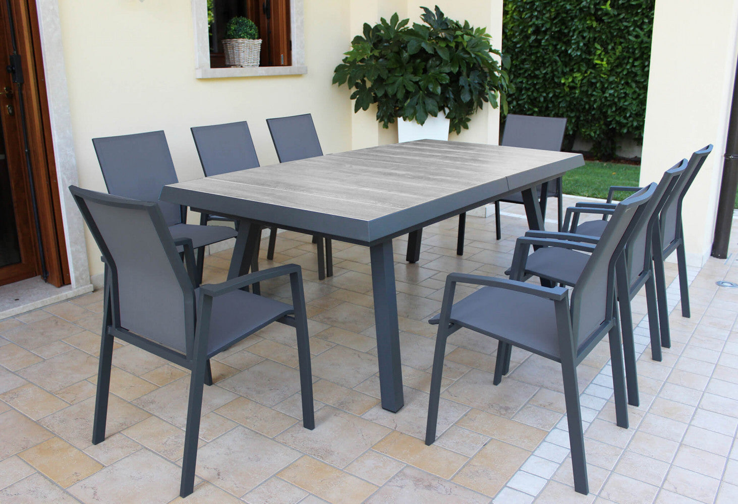Prospettiva angolare del tavolo da giardino Seattle su un patio elegante con piante decorative.