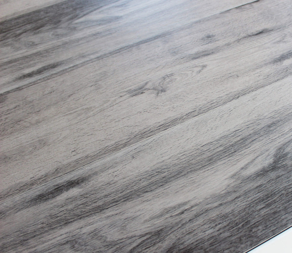 Primo piano della texture materica del gres porcellanato con finitura effetto legno grigio.
