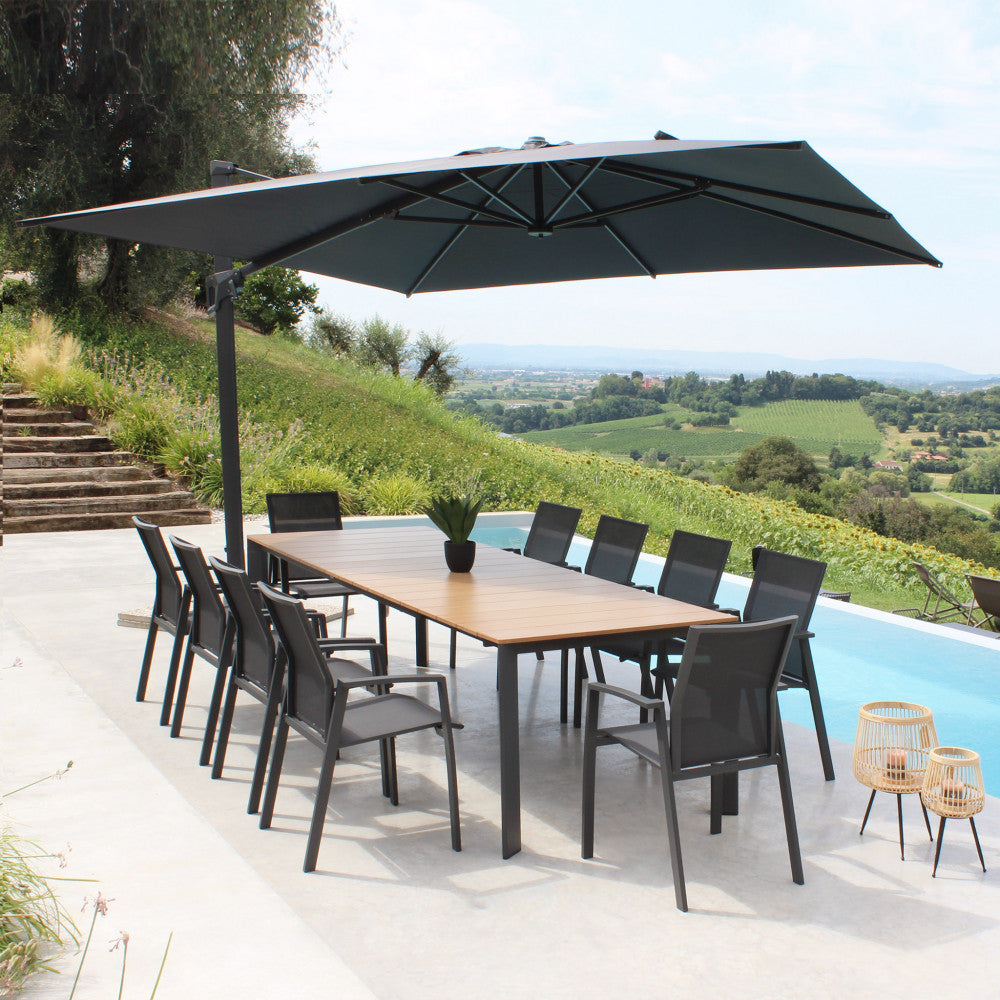 Tavolo Tulcán allungato a bordo piscina, ombreggiato da un grande ombrellone di design.