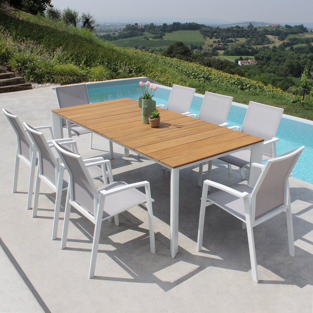 Elegante tavolo da pranzo in teak Tulcán con sedie bianche a bordo piscina con vista panoramica.