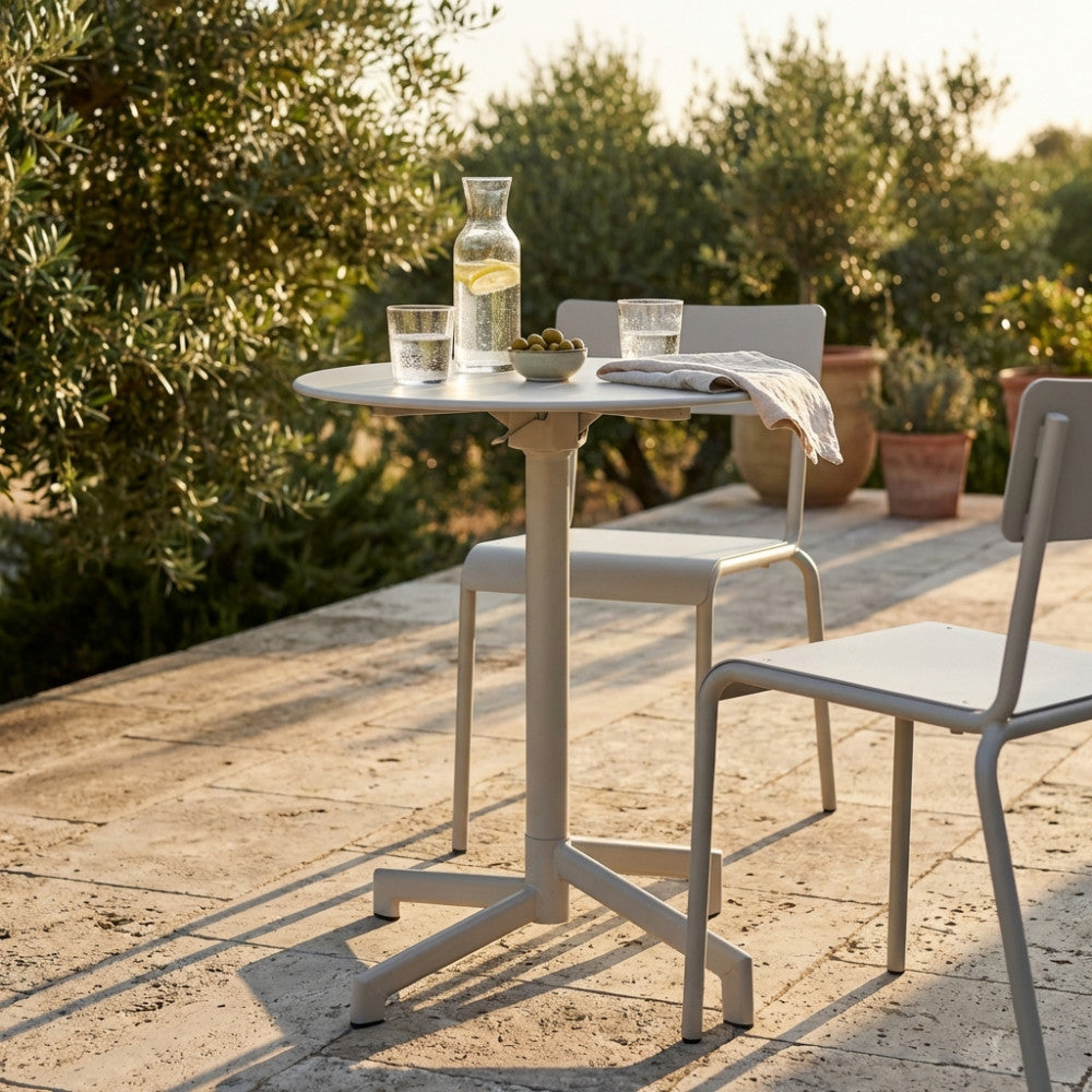 Dettaglio del tavolo da esterno Vega con bicchieri e decorazioni naturali sotto la luce del tramonto.