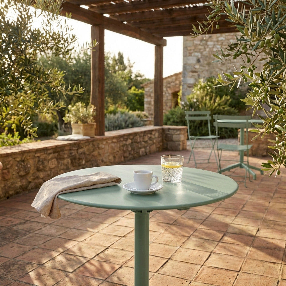 Dettaglio del tavolo da giardino rotondo con tazzina da caffè e bicchiere d'acqua.