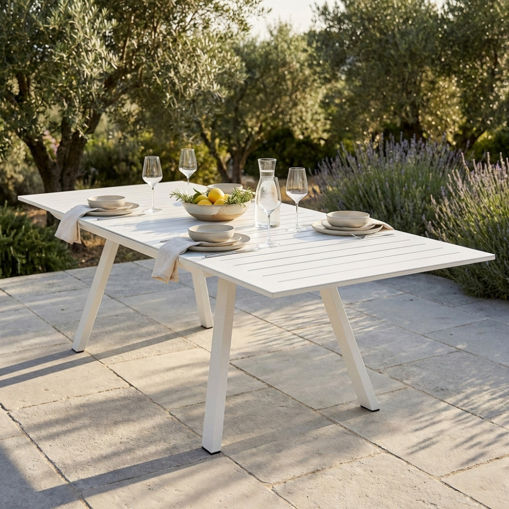 Tavolo da giardino Zante in alluminio bianco allestito per un pranzo all'aperto su una terrazza in pietra.