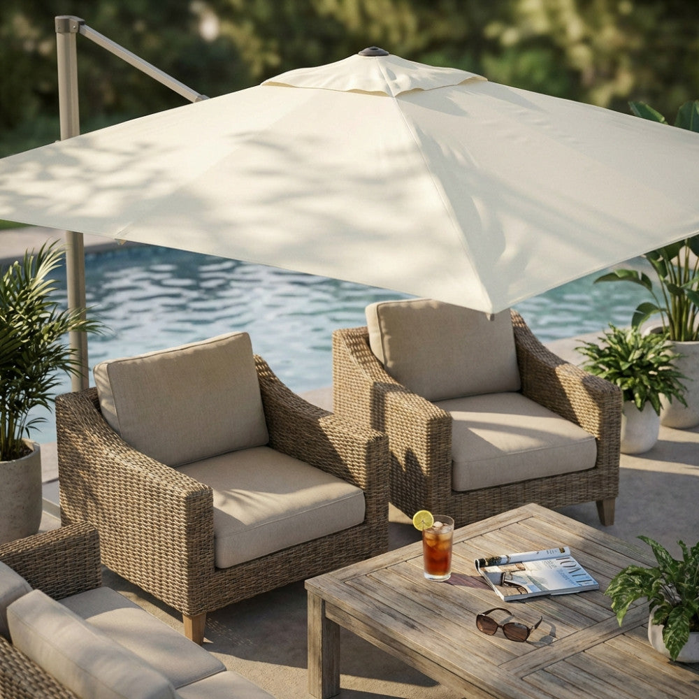 Dettaglio del telo ombrellone in poliestere beige che fa ombra su due poltrone in rattan vicino a una piscina.
