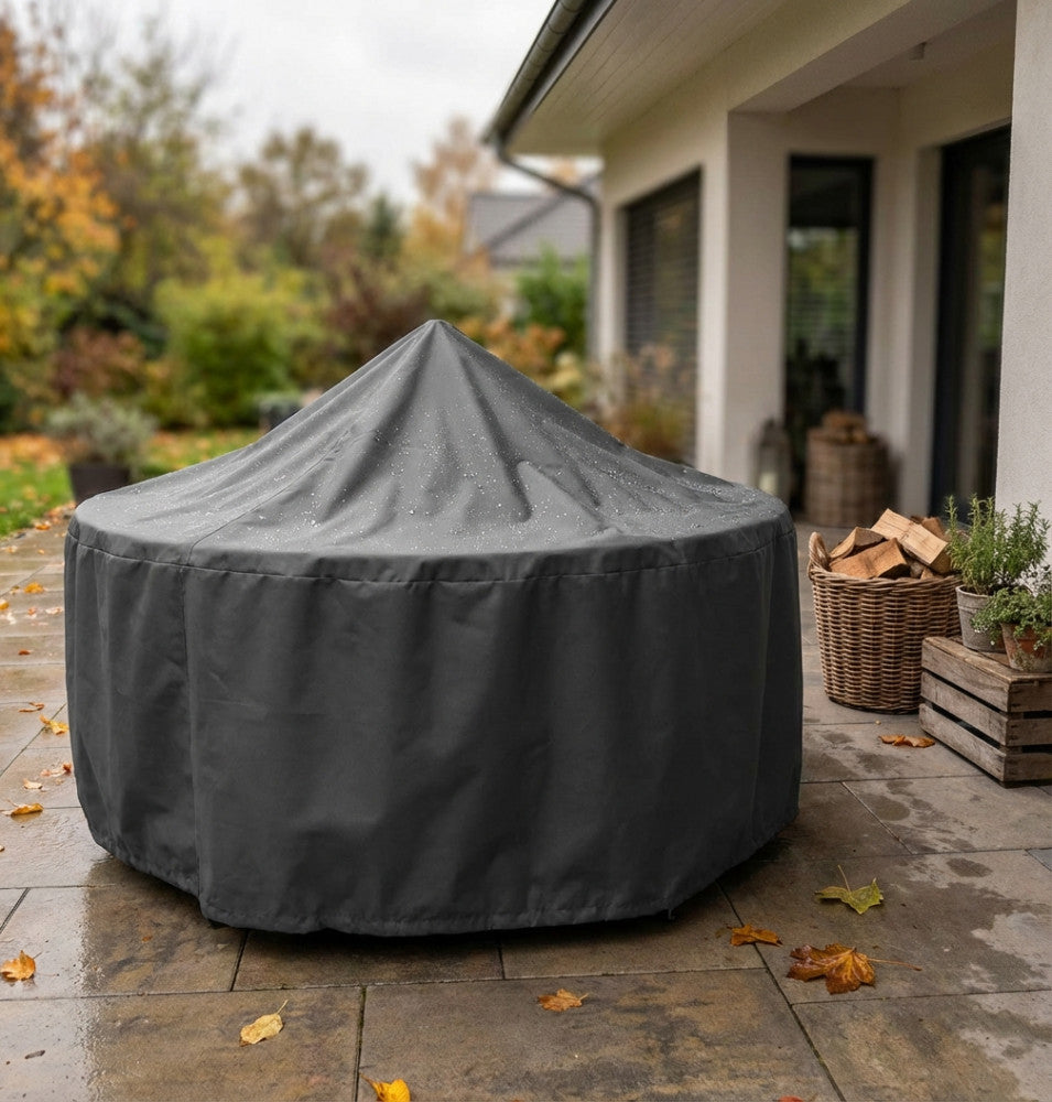 Telo copertura per tavolo rotondo in tessuto antracite posizionato su un arredo da giardino, con gocce d'acqua che scivolano sulla superficie.