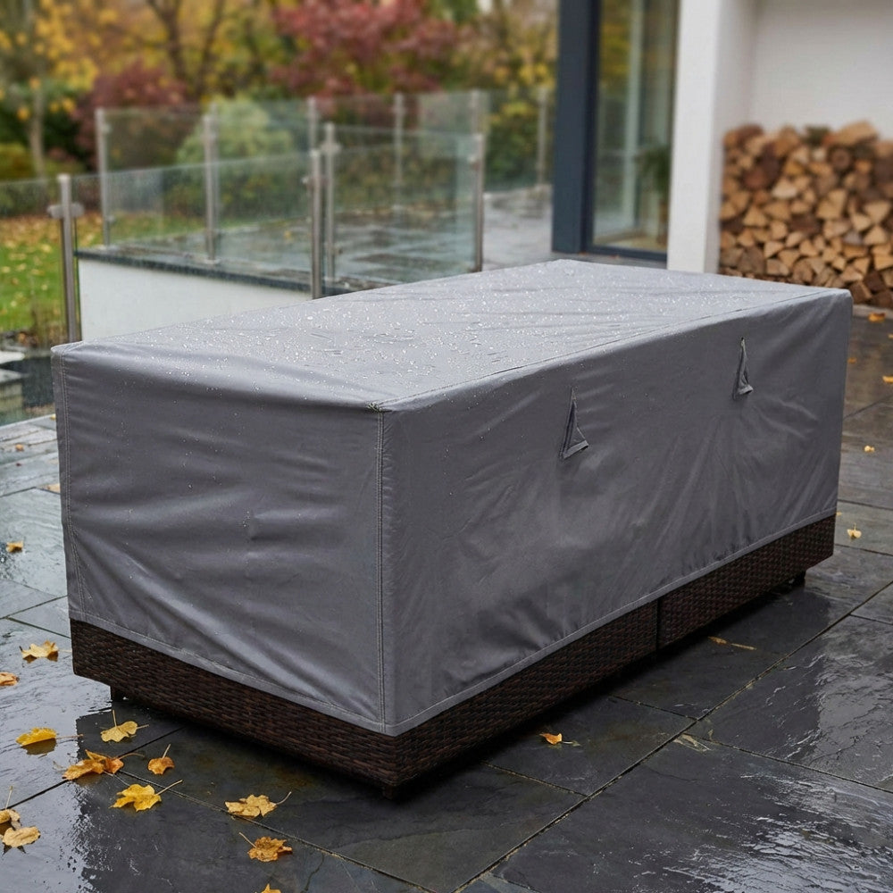 Telo di copertura per divano in tessuto antracite posizionato su un arredo da esterni, con gocce di pioggia sulla superficie idrorepellente.