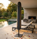 Telo di copertura per ombrellone in tessuto antracite posizionato a bordo piscina al tramonto, accanto a lettini dal design moderno.