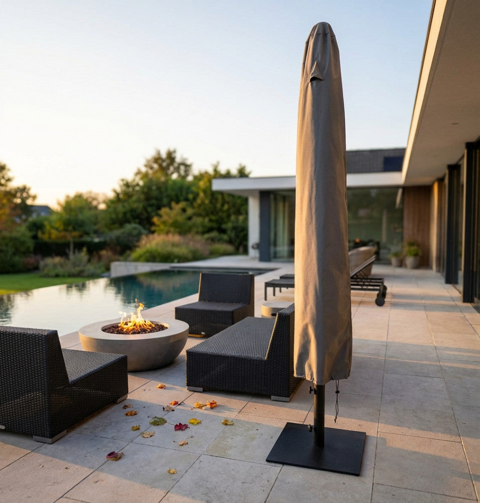 Copertura per ombrellone CO803019 in tessuto scuro, integrata in un'elegante area lounge esterna con braciere acceso e sedute intrecciate.