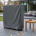 Telo di copertura per ping pong in tessuto antracite posizionato su un patio esterno con foglie autunnali e racchette in primo piano.