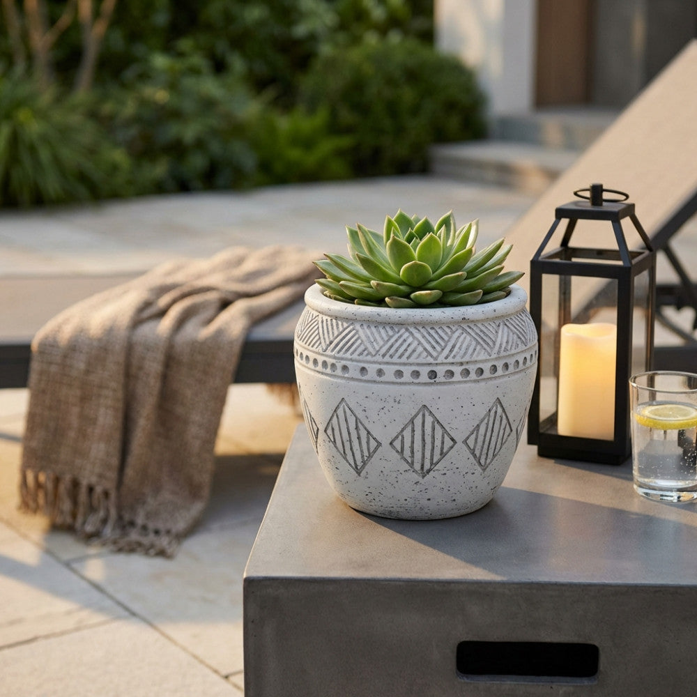 Dettaglio del Vaso Girasole grigio con motivi geometrici, ambientato all'aperto accanto a una lanterna decorativa e un bicchiere d'acqua.