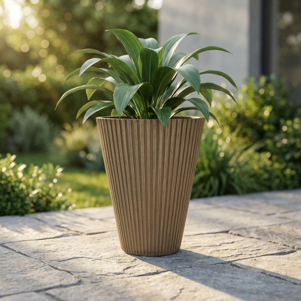 Vaso Grande Iris in fibra sintetica taupe con pianta verde su pavimentazione in pietra.