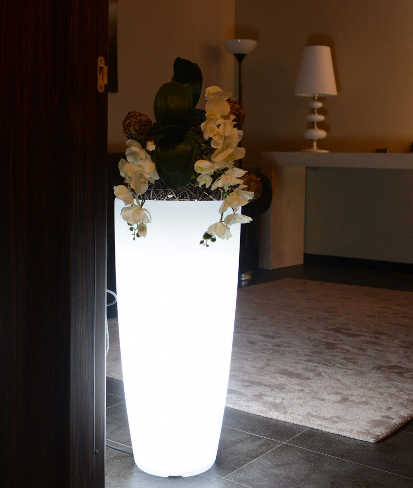 Vaso luminoso da interno con luce bianca fredda, decorato con orchidee, situato in un ingresso elegante.