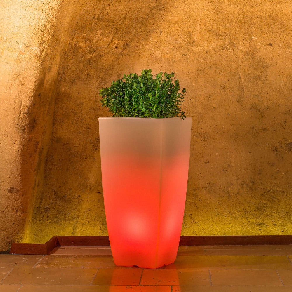 Vaso luminoso in polipropilene che emette una vibrante luce rossa, creando un'atmosfera calda in un ambiente con pareti in tufo.