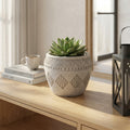 Vaso Medio Girasole in fibra sintetica grigia con pattern geometrici, posizionato su una consolle in legno di rovere con una pianta succulenta.
