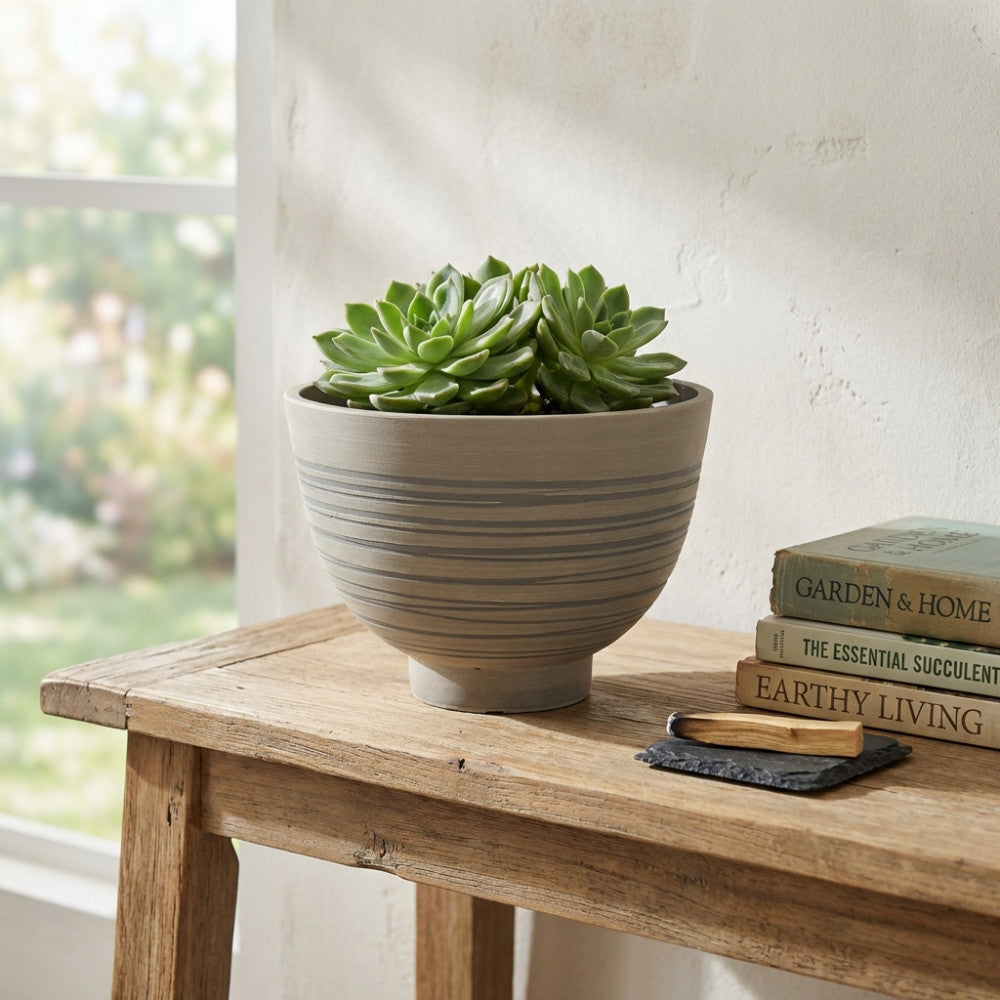 Vaso Narciso in fibra sintetica antracite con striature orizzontali, posizionato su un tavolo in legno rustico con piante succulente all'interno.