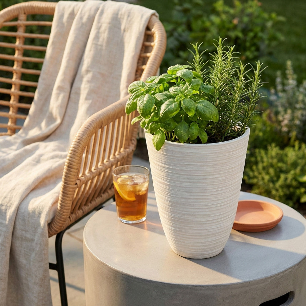 Dettaglio del Vaso Anemone bianco su un tavolino rotondo accanto a una poltrona in rattan, illuminato dalla calda luce del tramonto.