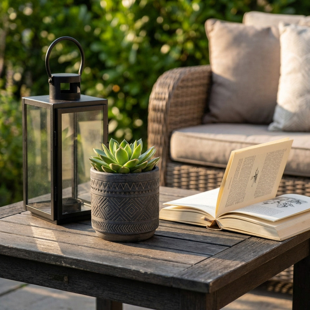 Vaso decorativo Melissa color antracite ambientato su un tavolo in legno scuro accanto a una lanterna e un libro aperto.