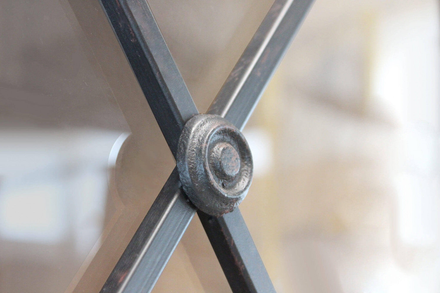 Particolare del rosone in metallo lavorato all'incrocio delle linee geometriche sull'anta in vetro trasparente.